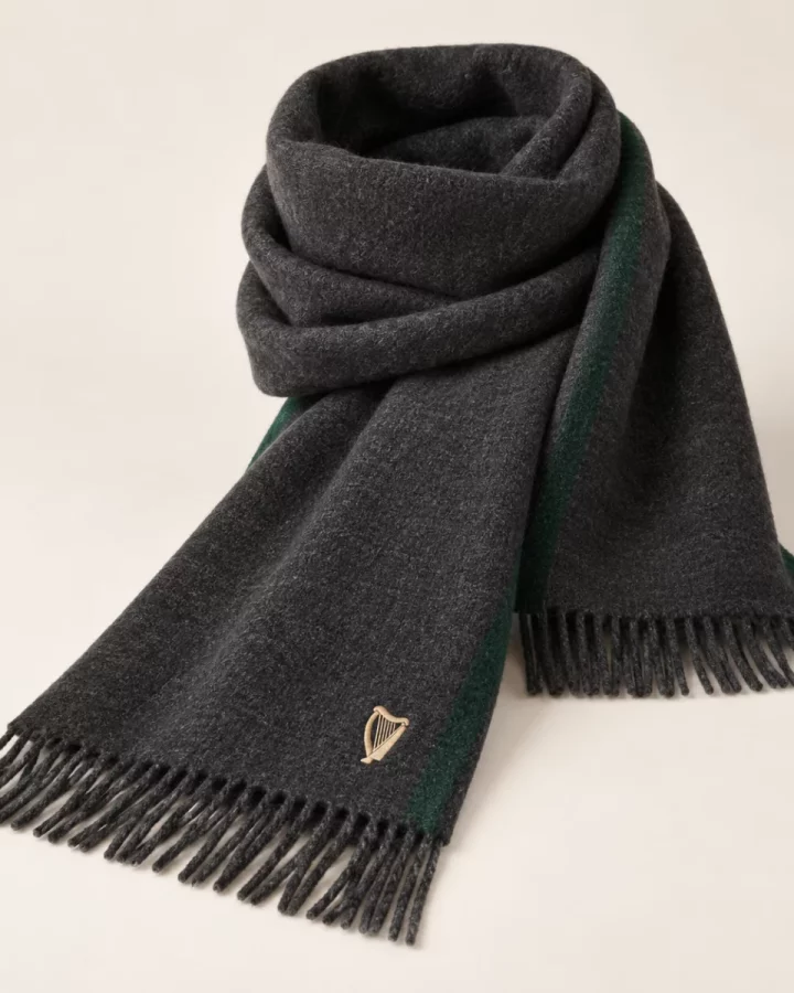 Charcoal District Winter Scarf design mock-up: Charcoal scarf; forest-green edge stripe; small harp at one end